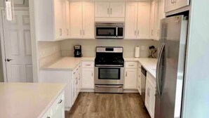 A modern kitchen with white cabinets, stainless steel appliances, and a wooden floor. - Luxury 4 Bedroom + Hot Tub. (El Dorado Hills)