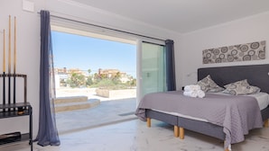 Una camera da letto con un letto, cuscini, un comodino e vista sull'esterno.
