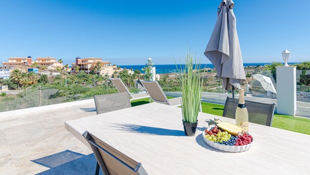 Una terrazza con un tavolo apparecchiato per un pasto, con vista sulla costa.