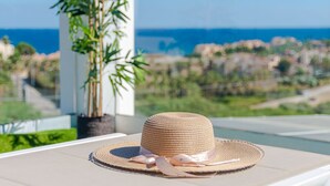 Un cappello di paglia su un lettino con vista sul mare e sugli edifici sullo sfondo.