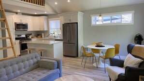 A modern kitchen with white cabinets, stainless steel appliances, and a central island. - Roberts Creek Cottage. Close to village, beach, hiking and biking trails. (Roberts Creek)
