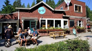 A rustic building with a 'Gumbo Cafe' sign, outdoor seating, and a 'Rock Gem' sign. - Roberts Creek Cottage. Close to village, beach, hiking and biking trails. (Roberts Creek)