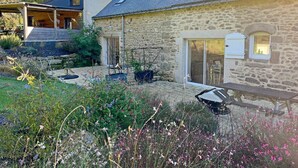 A stone house with a garden, a patio with a table and chairs, and a covered outdoor seating area. - L'optimist - Pluneret (PLUNERET)