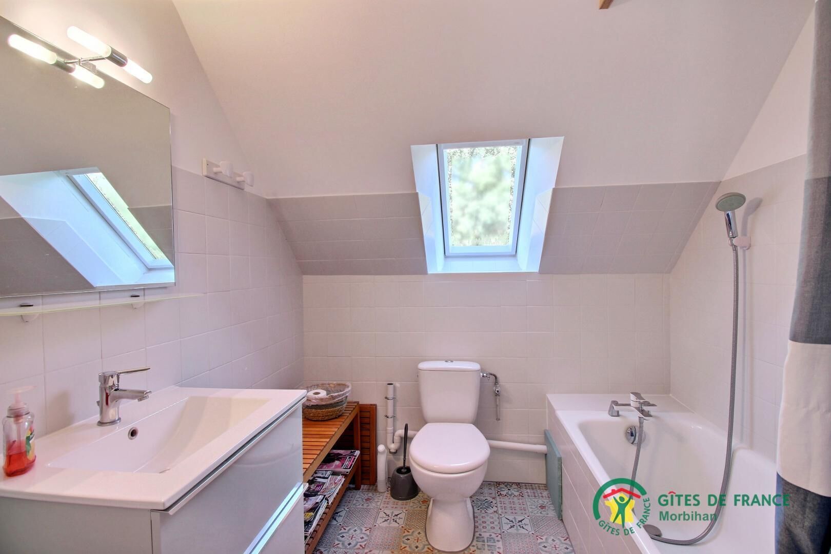 A modern bathroom with a skylight, a toilet, a sink, and a bathtub.