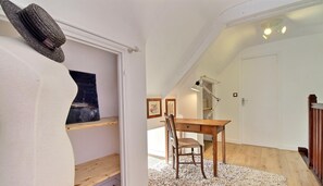 Une chambre aménagée en mezzanine avec un bureau en bois, une chaise et un chapeau accroché au mur.