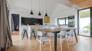Une cuisine moderne dotée d’un îlot central, de luminaires suspendus et offrant une vue sur l’extérieur.