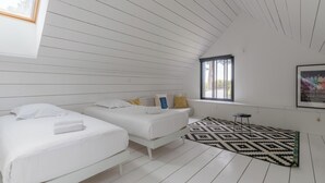 Une chambre avec deux lits, une fenêtre, un tapis à motifs et un tableau encadré au mur.