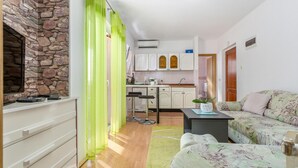 A compact living space with a stone wall, a kitchenette, a sofa, and a dining area. - Awesome apartment in Krk with WiFi (Krk)