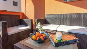 A wicker outdoor seating area with cushions, a bowl of fruit, a book, and a small potted plant. - Awesome apartment in Krk with WiFi (Krk)