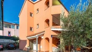A multi-story building with a flat roof, a balcony on the second floor, and a door with a number sign. - Awesome apartment in Krk with WiFi (Krk)