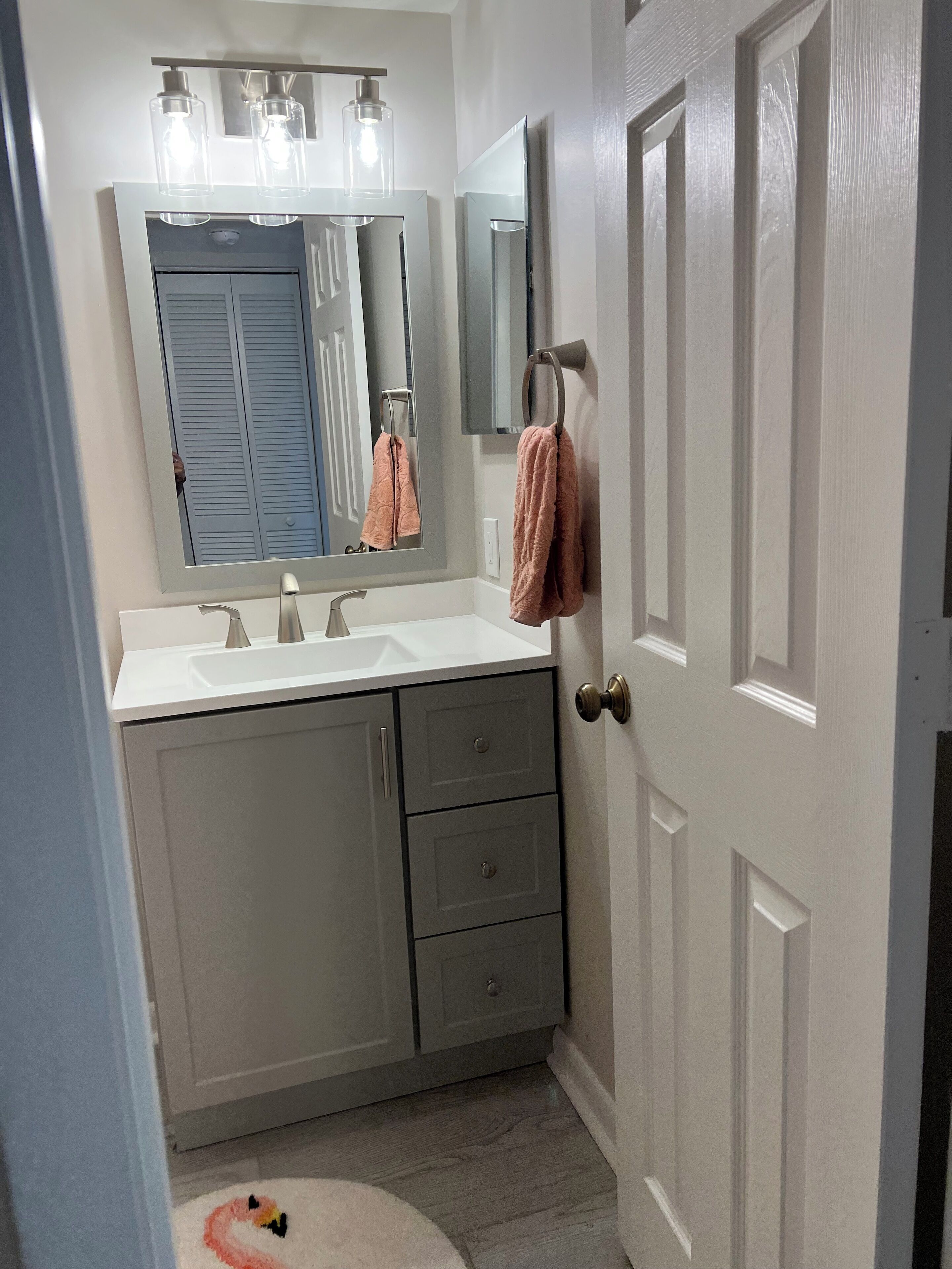 A bathroom with a double sink vanity, a large mirror, and a towel rack.
