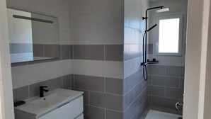 Ein modernes Badezimmer mit Waschbecken, Spiegel und Dusche.