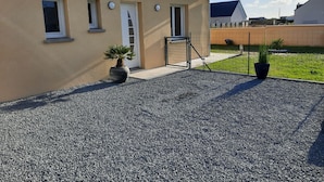 Ein Haus mit Kiesweg, Tor und zwei Blumentöpfen.