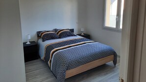 Ein Schlafzimmer mit einem Bett, zwei Nachttischen, einem Fenster und einer Tür.