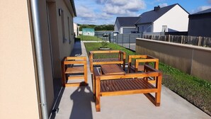 Eine Terrassenfläche mit Holzmöbeln, einem Betonboden und Blick auf benachbarte Häuser.