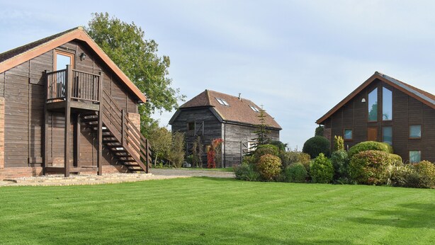 Een gebouw met een houten gevel, een zichtbare trap en een verzorgd gazon.