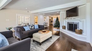 A modern living room with a fireplace, a sofa set, and a Christmas tree.