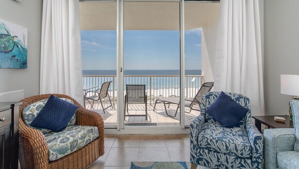 A balcony with wicker chairs, a patterned armchair, and a view of the ocean. - Relaxing Gulf Views at the Beach Club in Fort Morgan! (Gulf Shores)