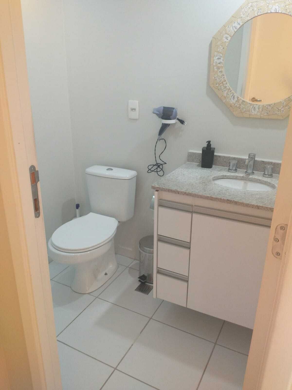 A small, clean bathroom with a toilet, sink, and mirror.