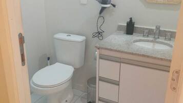 A small, clean bathroom with a toilet, sink, and mirror.