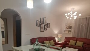 A modern living room with a glass dining table, red sofa, and a ceiling light fixture. - Relax & Home, Apartment with terrace and parking (La Zubia)