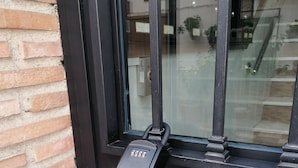 A glass door with a keypad lock, a brick wall, and a reflection of a building interior. - Relax & Home, Apartment with terrace and parking (La Zubia)