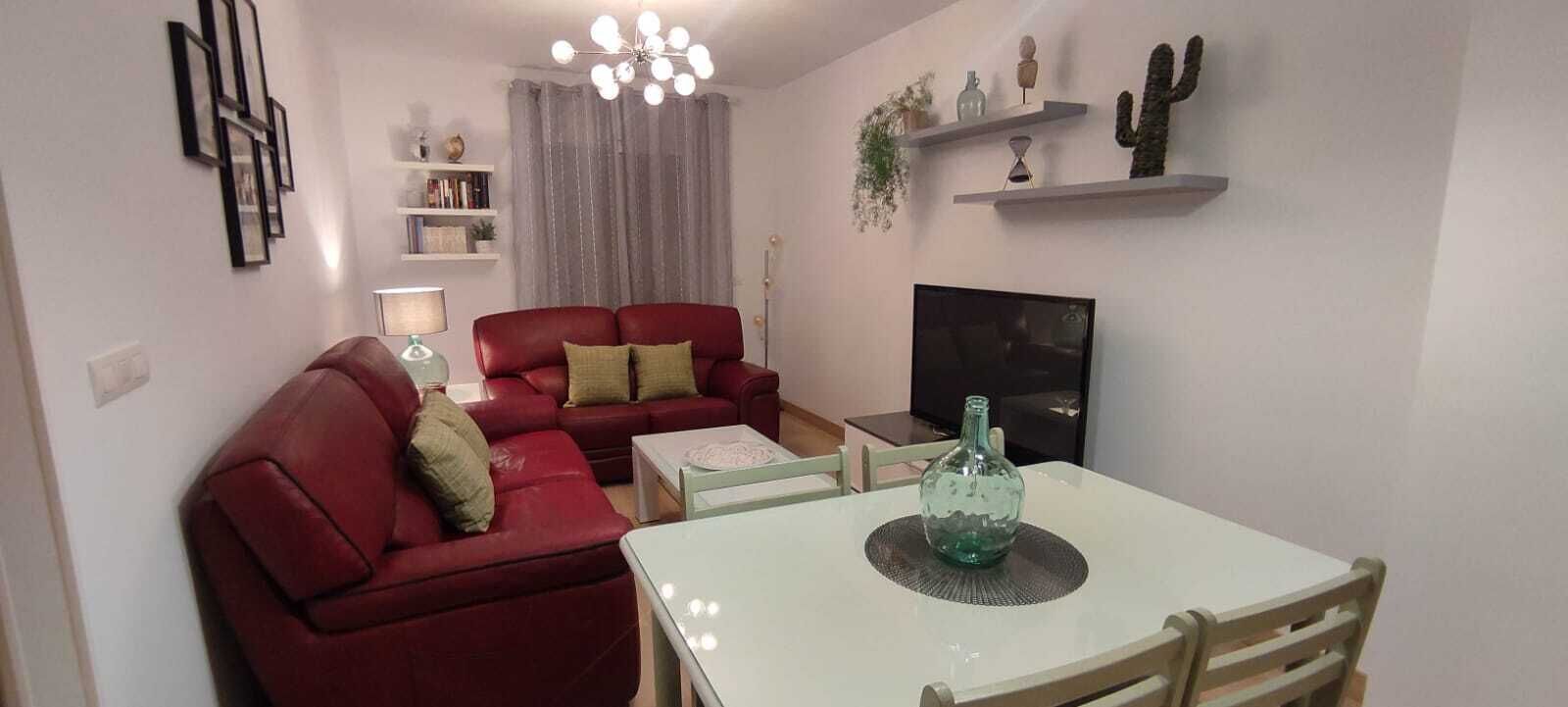 Un salon avec un canapé rouge, une table blanche et un téléviseur.