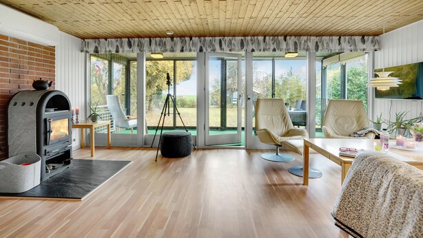 Ein modernes Wohnzimmer mit Kaminofen, großen Fenstern und bequemen Sitzmöglichkeiten.