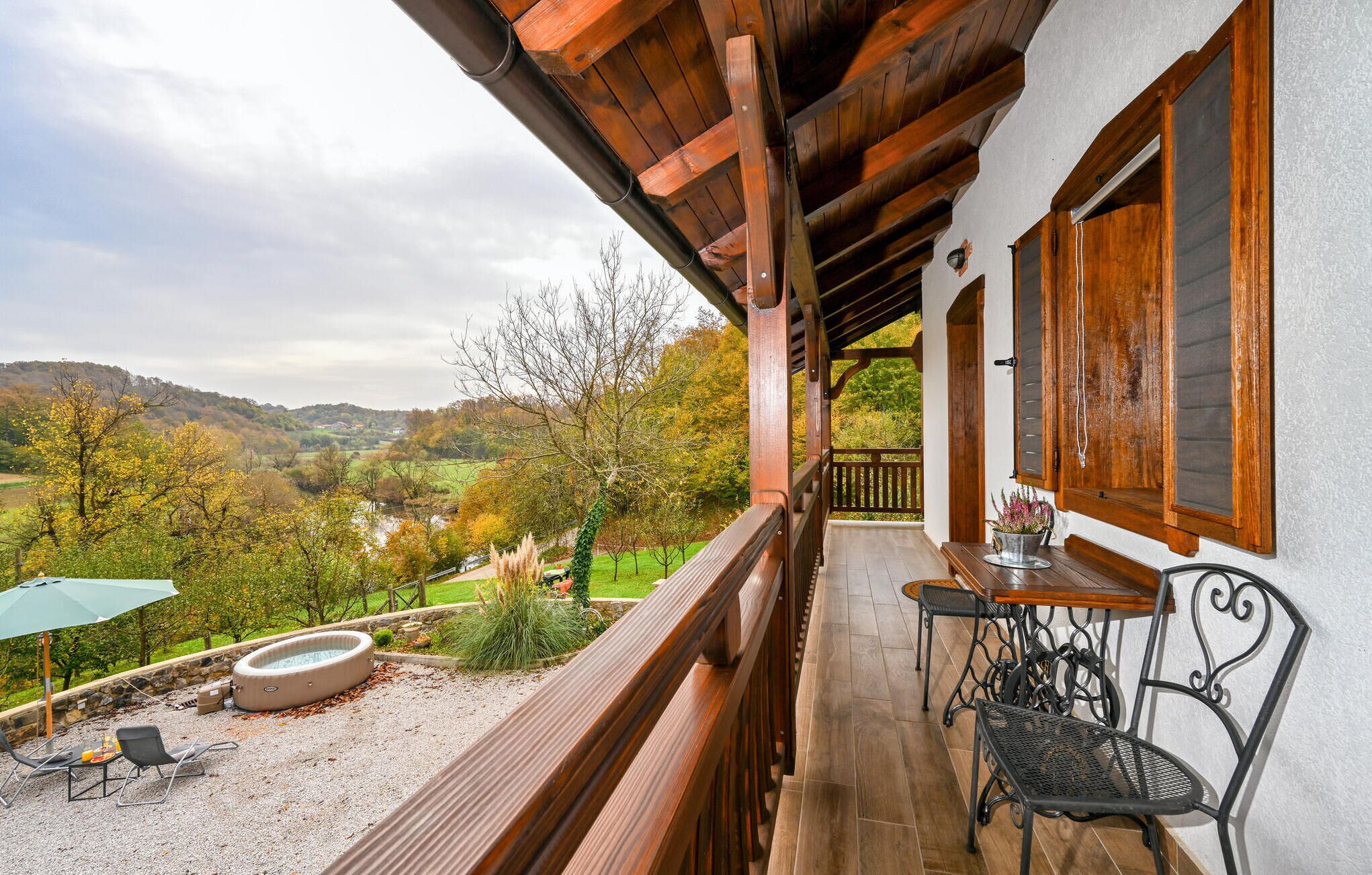 A balcony with a wooden railing, a table, and two chairs.