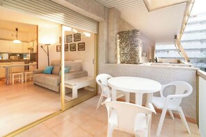 A modern interior with a dining area, a sofa, and a kitchen visible through a glass door.