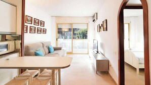 A modern living room with a sofa, a dining table, and a kitchen area with a microwave.