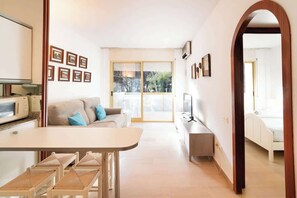 A modern living room with a sofa, a dining table, and a kitchen area with a microwave.