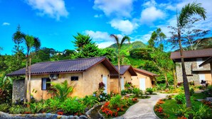 A bungalow-style building with a tiled roof, surrounded by lush greenery and a small water feature. - Rio Verde by Villa Alejandro (Los Naranjos)