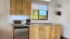 Una cocina compacta con armarios de madera, un microondas, una cafetera y un lavavajillas.