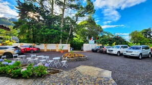 A parking area with multiple cars, outdoor seating, and a garden with flowers. - Rio Verde by Villa Alejandro (Los Naranjos)
