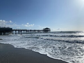 A pier extending into the ocean with a small structure at the end. - OCEANSIDE RETREAT*STEPS FROM THE BEACH*HEATED POOL (Cocoa Beach)