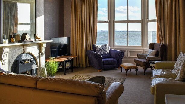 A living room with a fireplace, a television, and a view of the water.