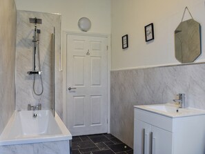 A bathroom with a bathtub, a shower, a sink, and a mirror on the wall. - 4 bedroom accommodation in Hartlepool (Hartlepool)