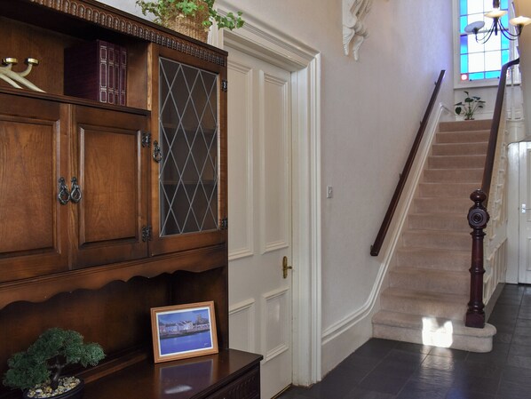 Un meuble en bois avec des portes en verre, un tableau encadré et un escalier avec une rampe en bois.