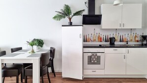 Eine moderne Küche mit weißen Schränken, einer schwarzen Arbeitsplatte und verschiedenen Flaschen.