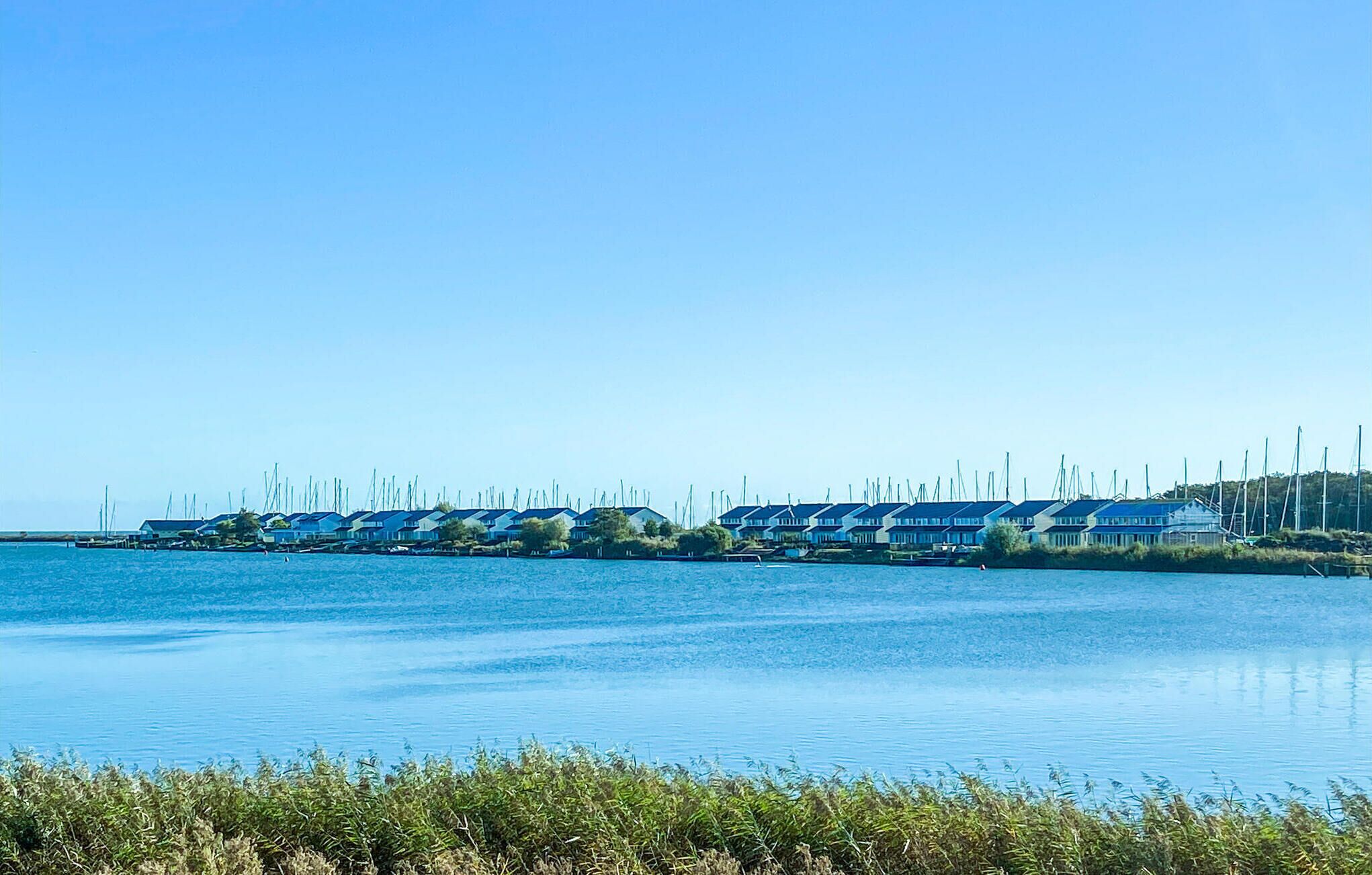 A row of blue-roofed houses by a calm body of water.