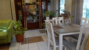 Un comedor con una mesa y sillas blancas, rodeado de plantas en macetas.