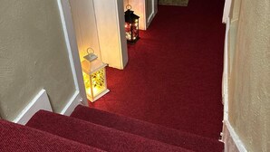 A staircase with red carpet leading to a landing. - Lovely Studio Apartment in London (London)