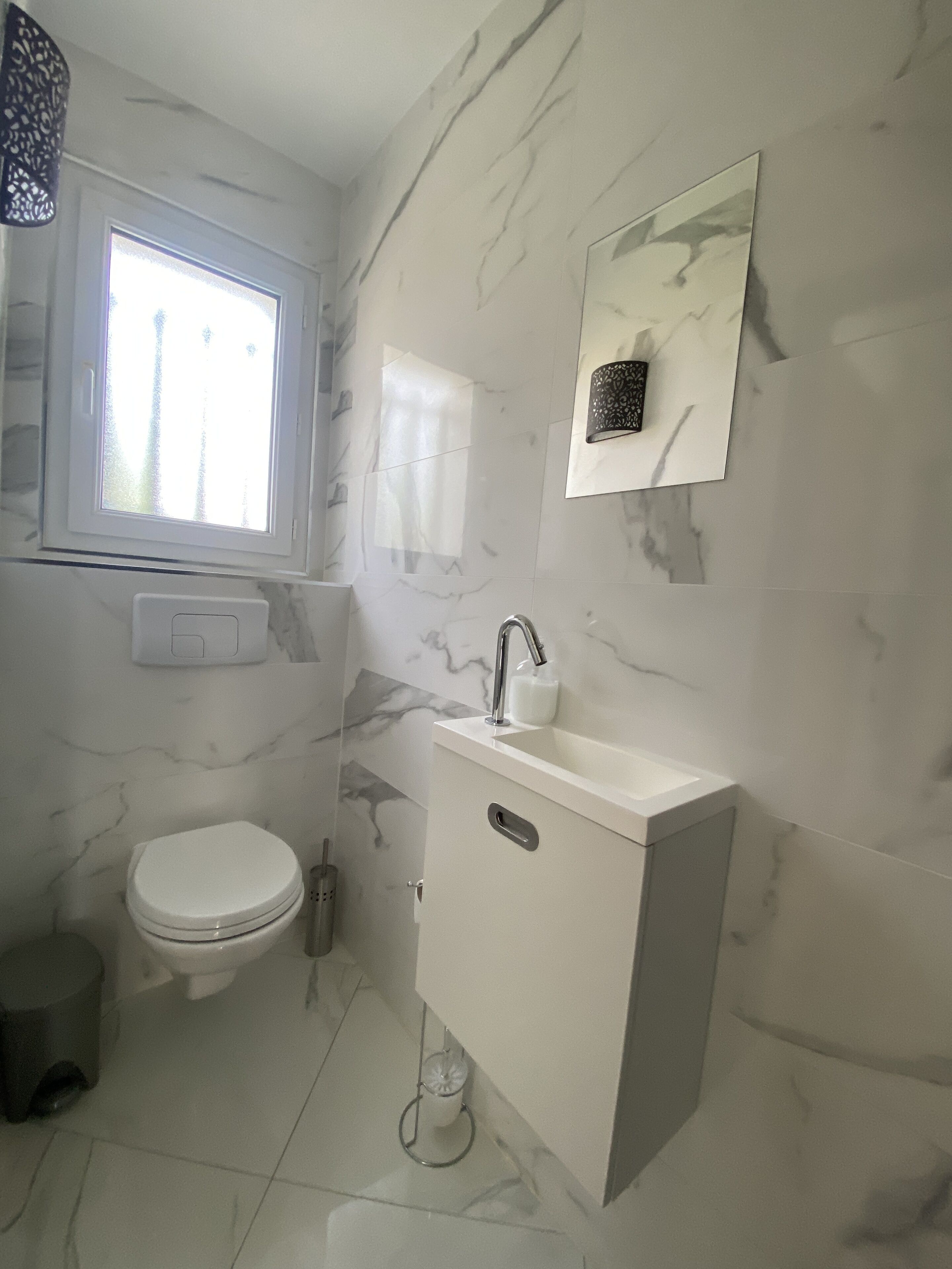 A modern bathroom with a toilet, sink, and window.