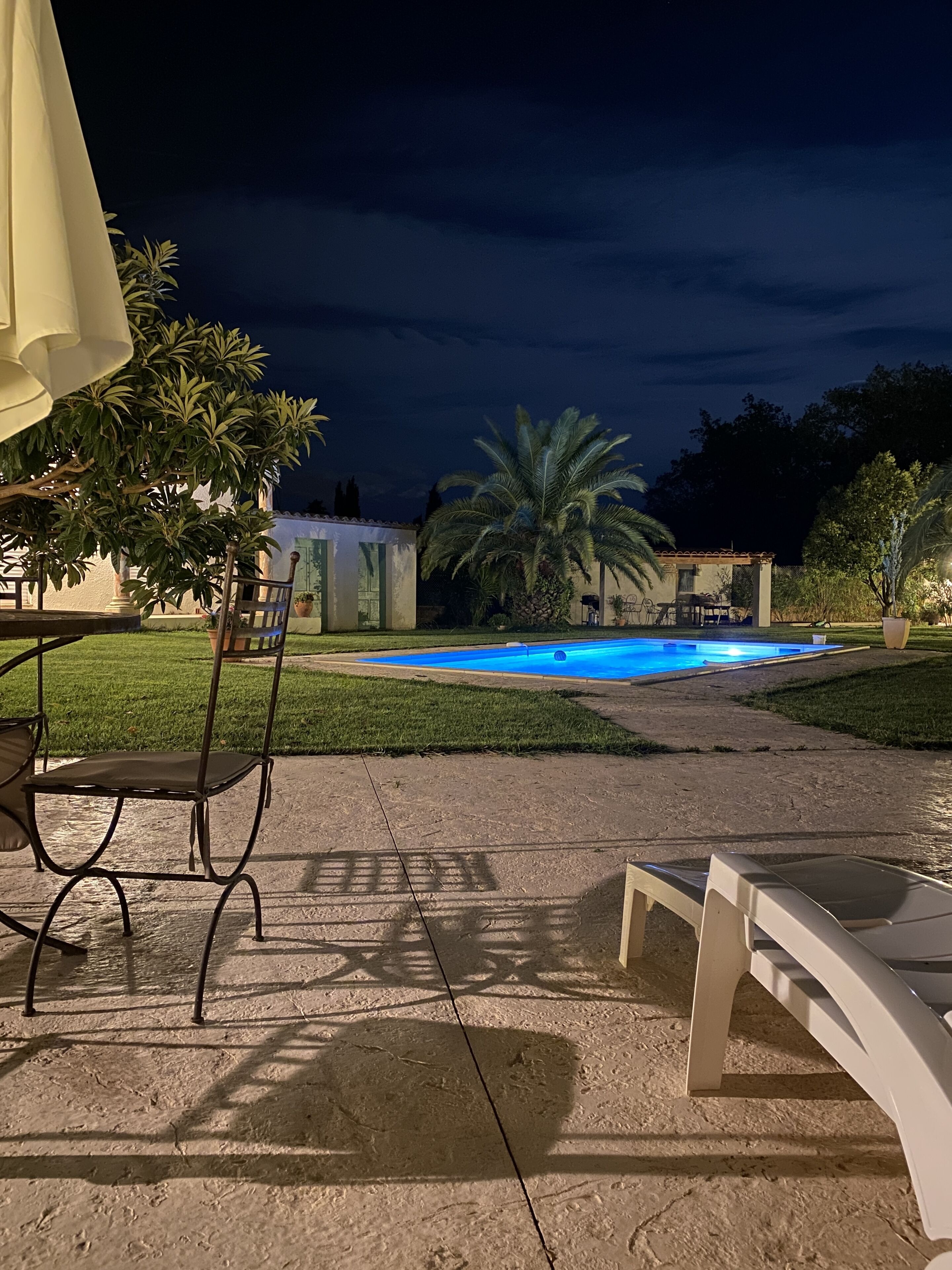 Een buitenzwembad met terras, stoelen en een tafel.