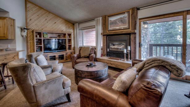 Ein gemütliches Wohnzimmer mit Kamin, Ledersofas, einem Fernseher und einer Wand aus Naturstein.