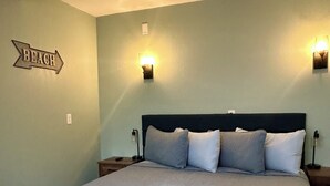 A bedroom with a bed, two nightstands, a wall-mounted light, and a directional sign. - EPIC Weeki Wachee riverfront home Waterfront Kayaks included (Spring Hill)
