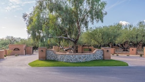 A landscaped area with a stone wall, a tree, and a paved driveway. - Woodland Rd 1882 Historic 12-acre ranch, Resort landscape views up to 30 ppl (Tucson)