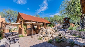An outdoor patio with stone seating, a barbecue area, and a covered shelter. - Woodland Rd 1882 Historic 12-acre ranch, Resort landscape views up to 30 ppl (Tucson)