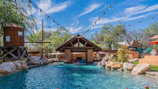 A pool area with a wooden structure, rocks, and string lights. - Woodland Rd 1882 Historic 12-acre ranch, Resort landscape views up to 30 ppl (Tucson)